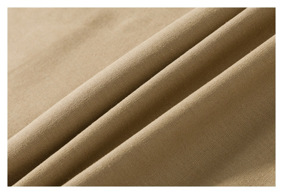 Close-up of tan fabric arranged in diagonal folds, showing its fine textured weave.