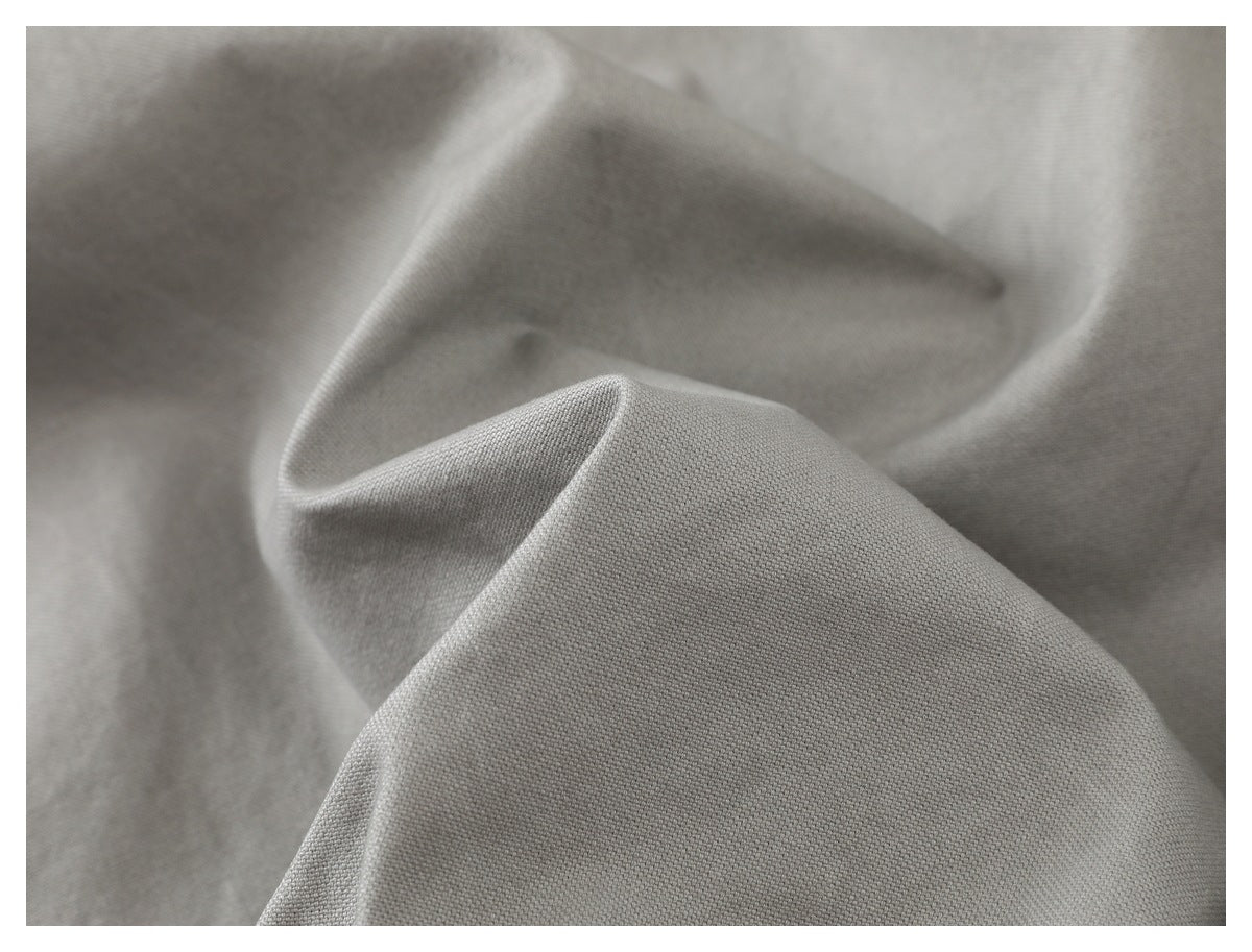 Macro view of the light gray garment fabric, showing its fine woven texture and folds.