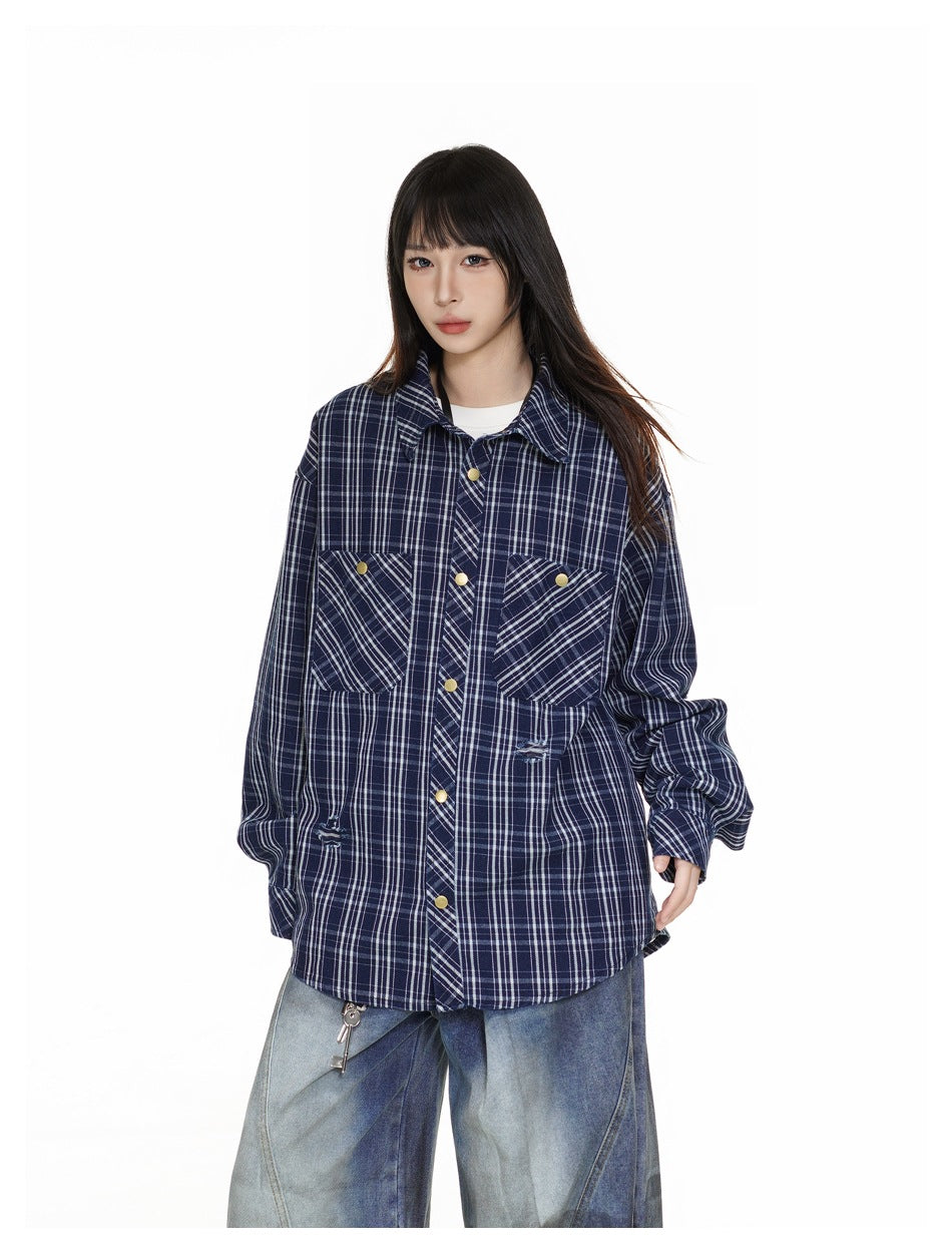 Front view of a model in an oversized navy-and-white plaid shirt with brass-tone snaps and angled chest pockets.