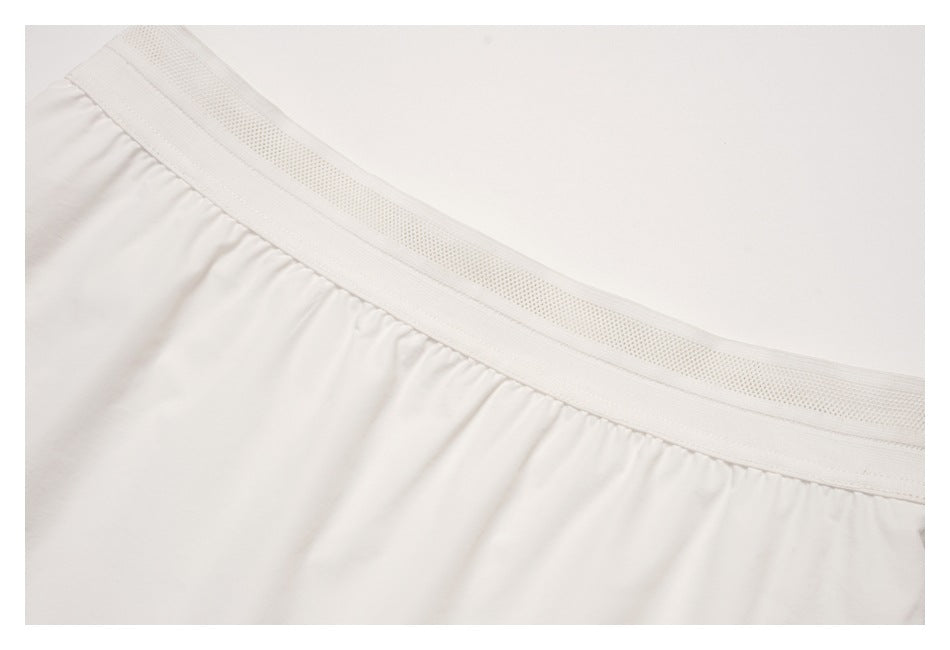 Close-up of the white skirt's wide perforated waistband and gathered fabric.