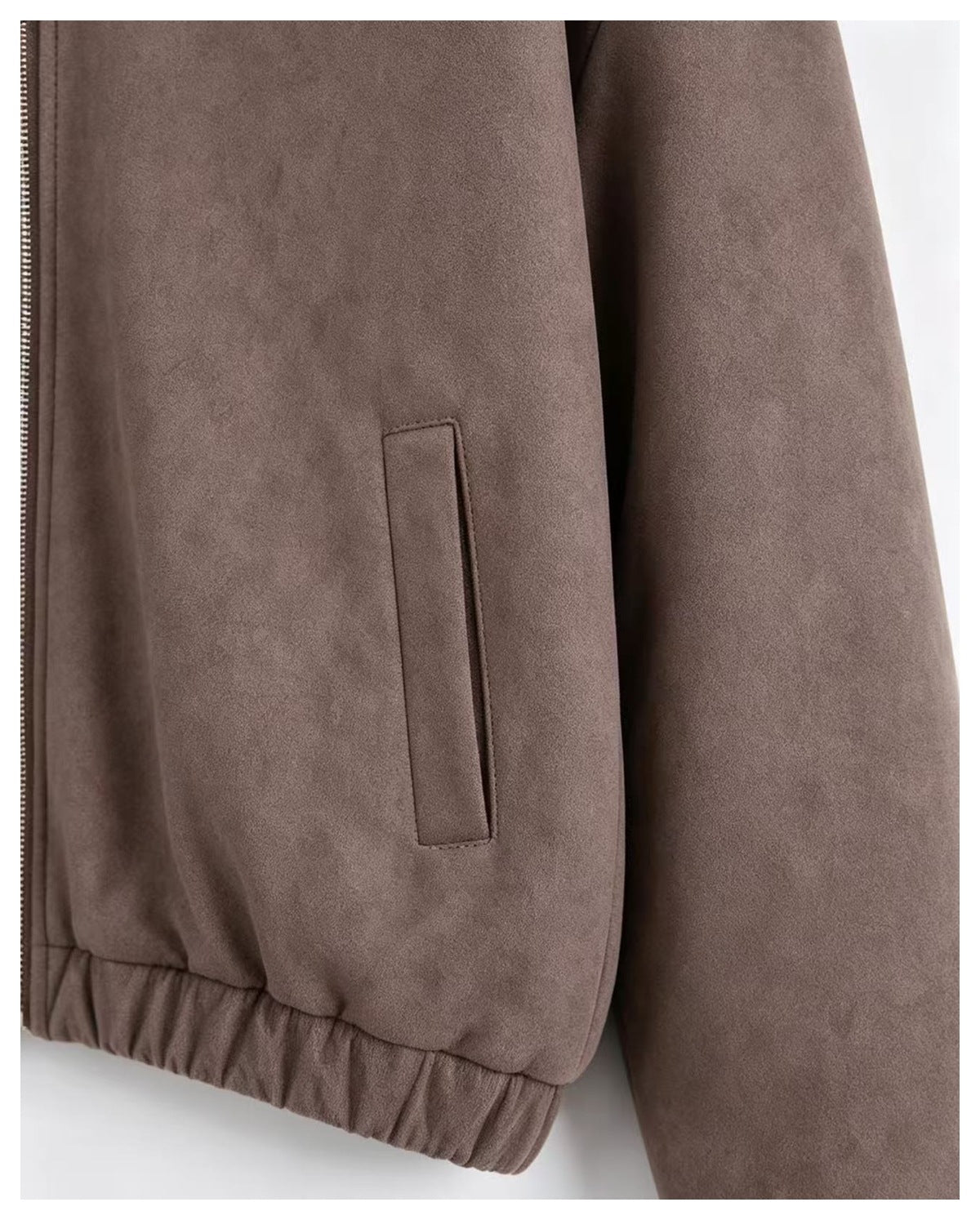 Close-up of the taupe jacket's vertical front pocket, zipper edge, and gathered hem.