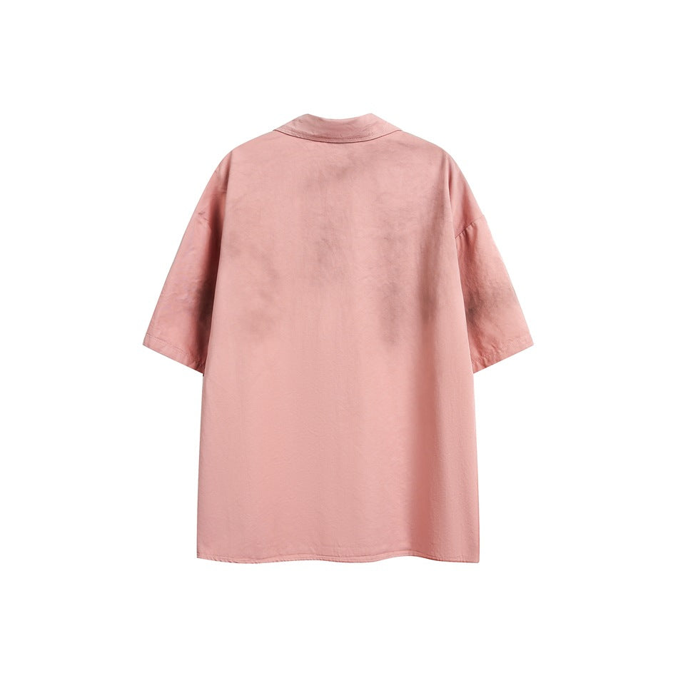 Back view of dirty pink short-sleeve shirt with dropped shoulders and gray sprayed distressed marks