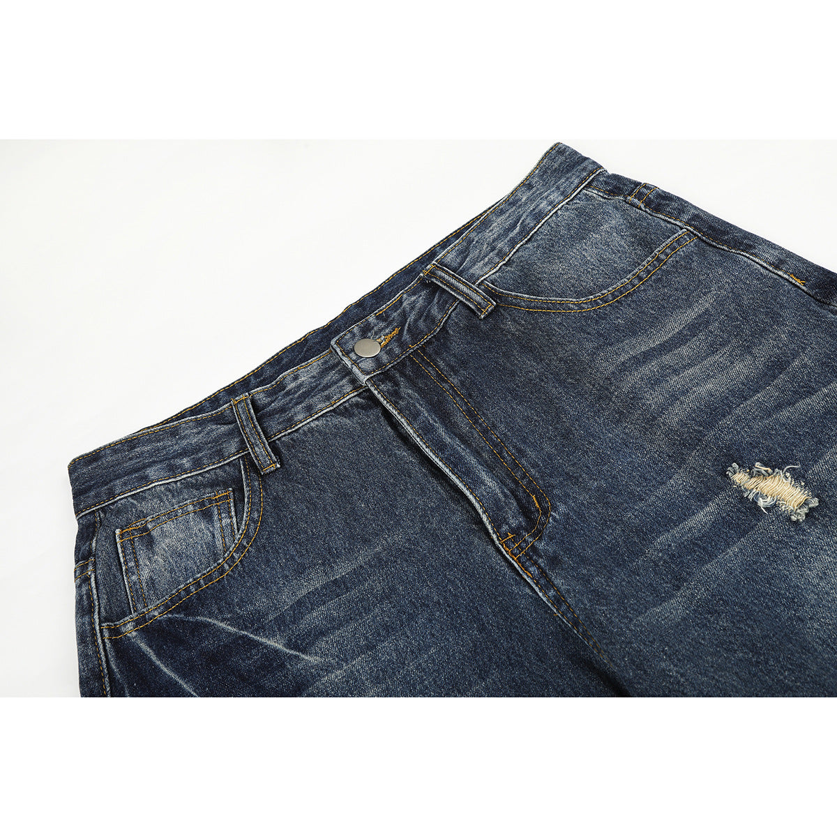 Close-up of dark blue distressed jeans showing the waistband, button, front pocket, and a frayed tear.