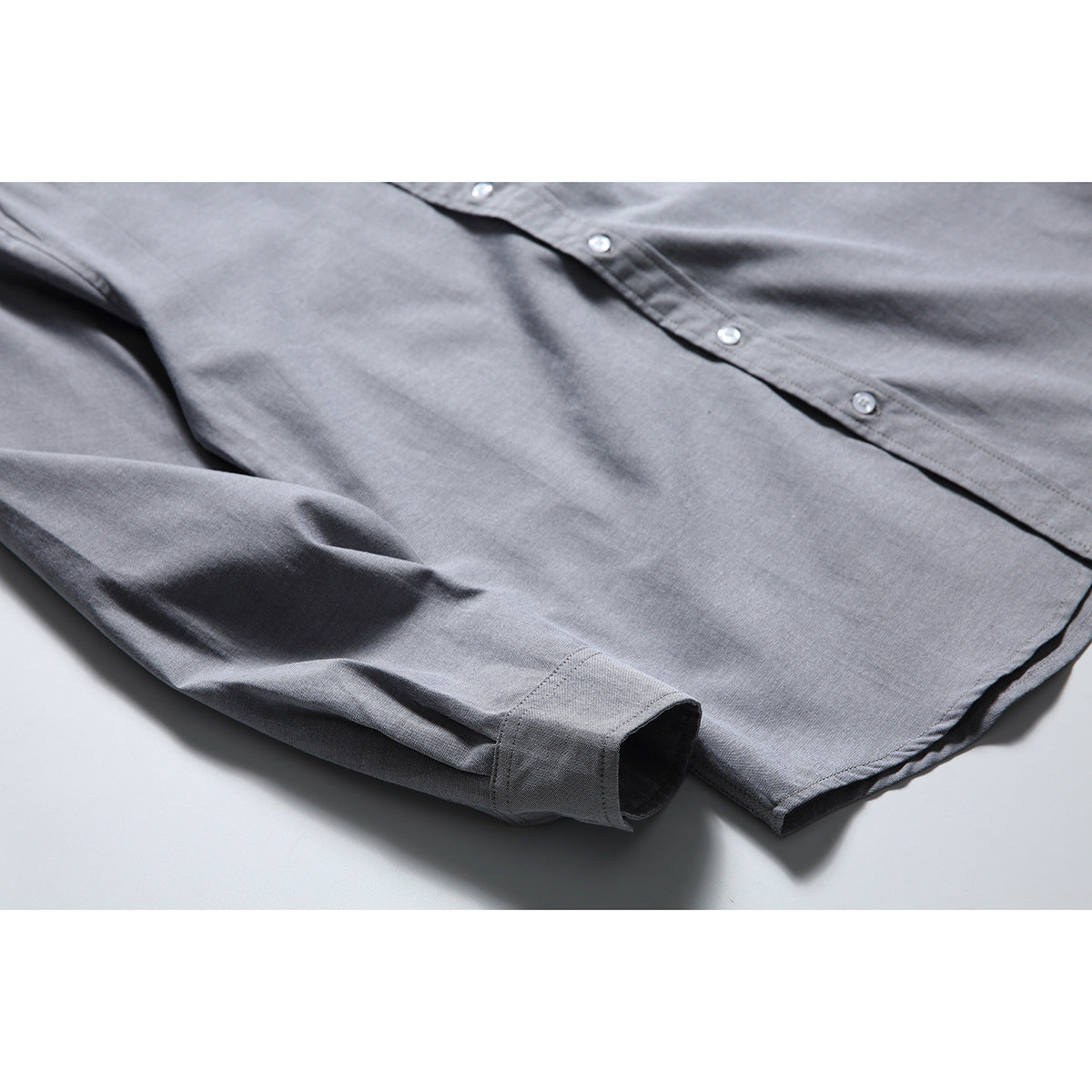 Close-up of the gray shirt's button placket, sleeve, cuff, and curved hem.