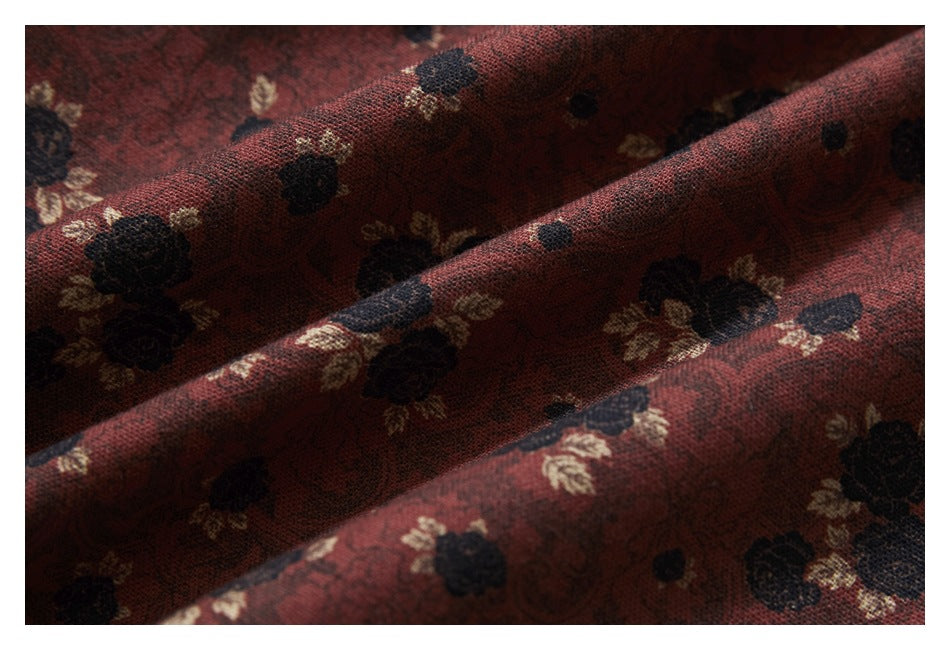 Close-up of burgundy fabric with a black and cream floral pattern and visible weave.