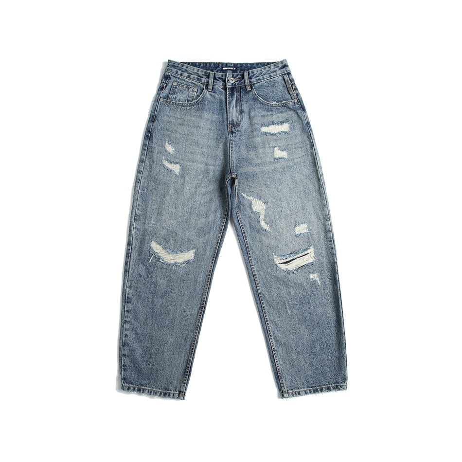 Front view of blue washed distressed denim jeans with ripped patches, belt loops and a slightly tapered leg