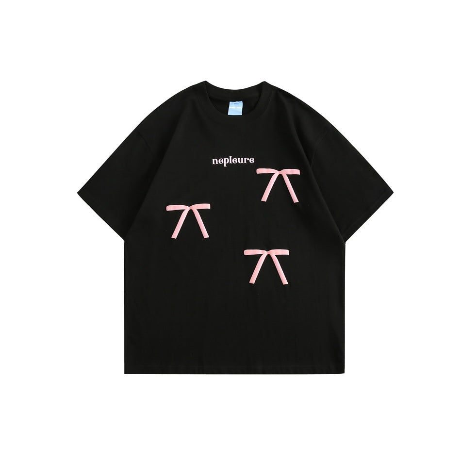 Black short-sleeve T-shirt with three pink ribbon bows and small white lettering on the front