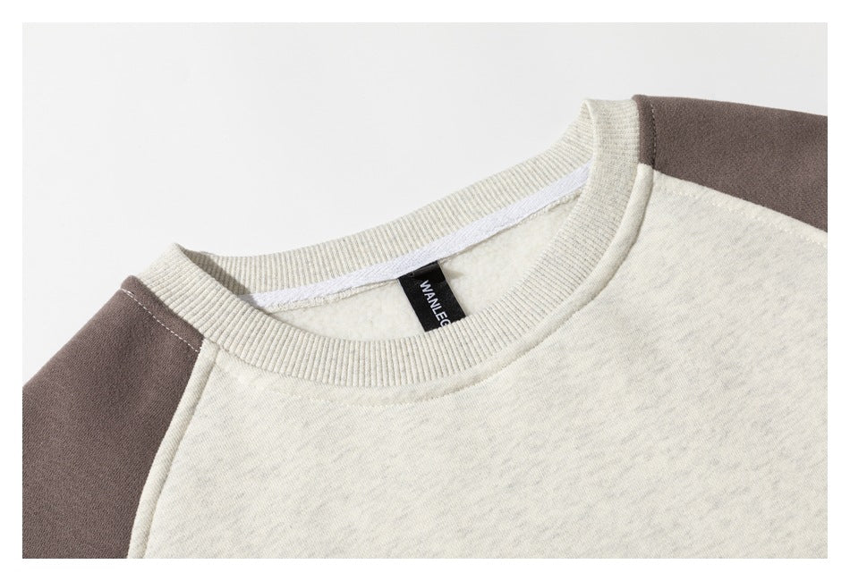 Close-up of the oatmeal sweatshirt's ribbed crew neck, inner label, and charcoal shoulder panels.