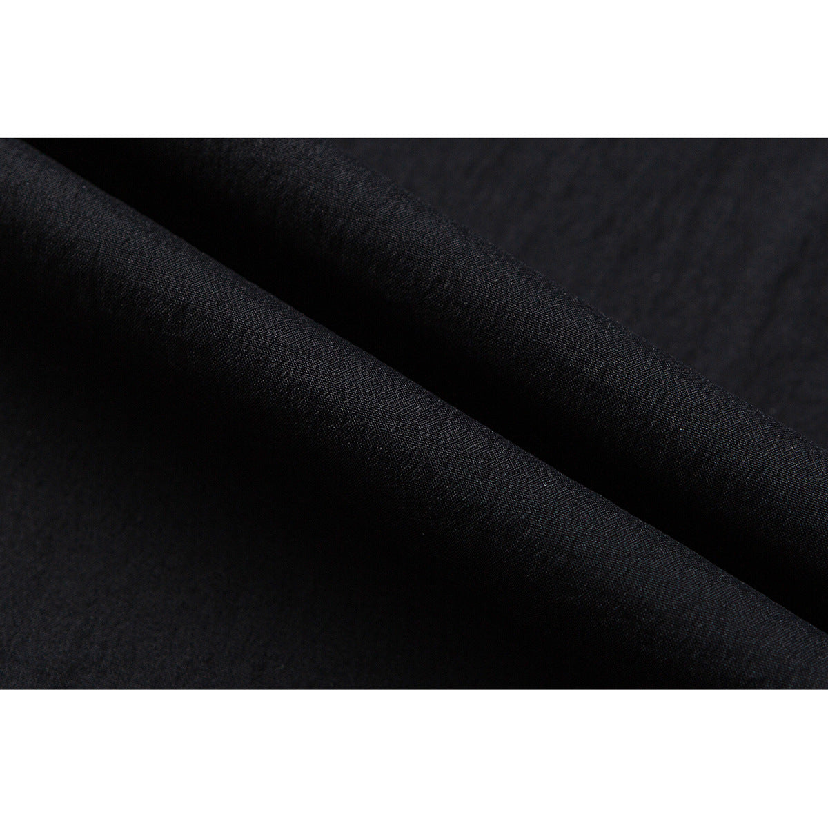 Macro view of dark black fabric folded to show its fine, subtly textured surface.