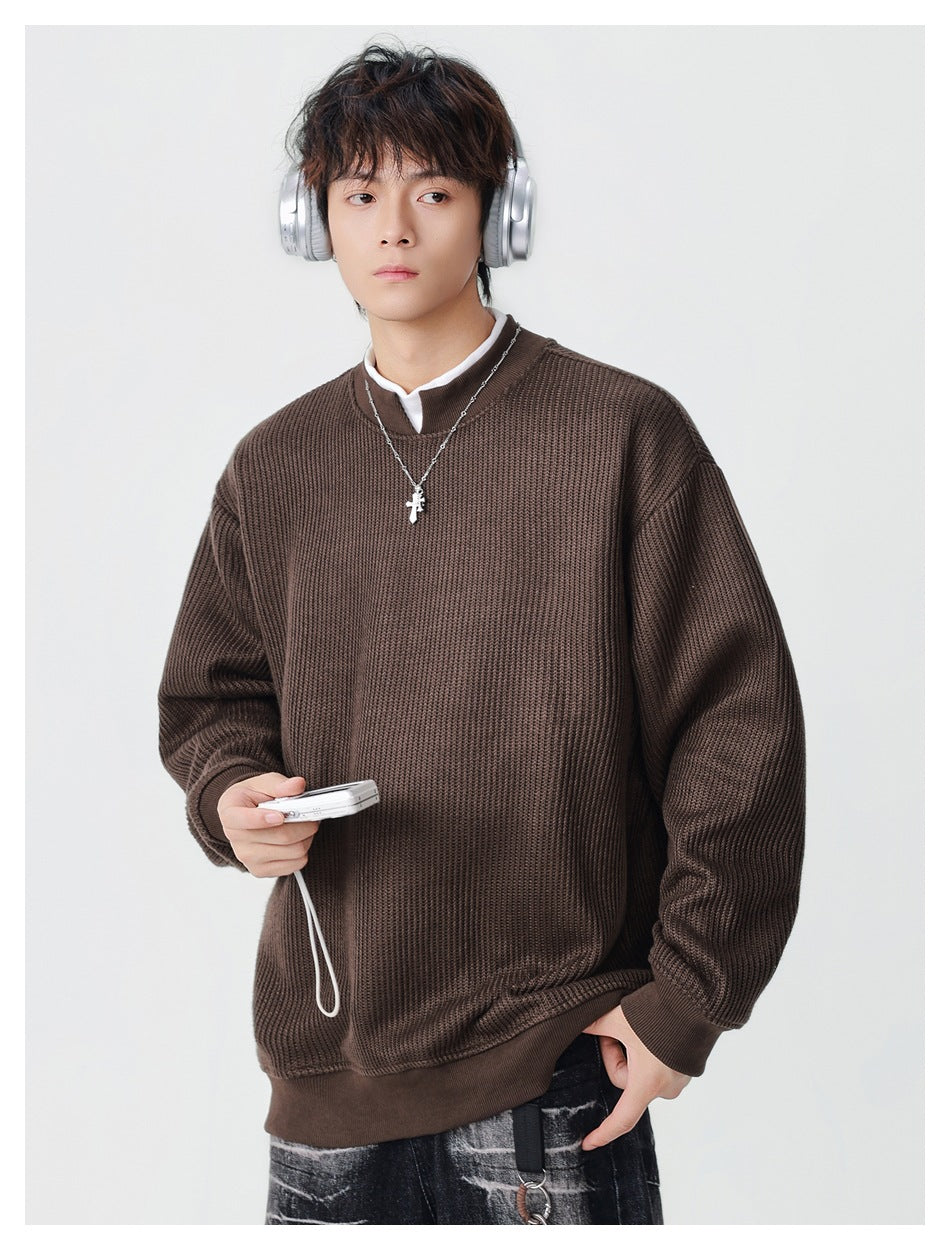 Model wearing a dark brown ribbed sweatshirt with a stand collar, silver headphones and a pendant necklace.