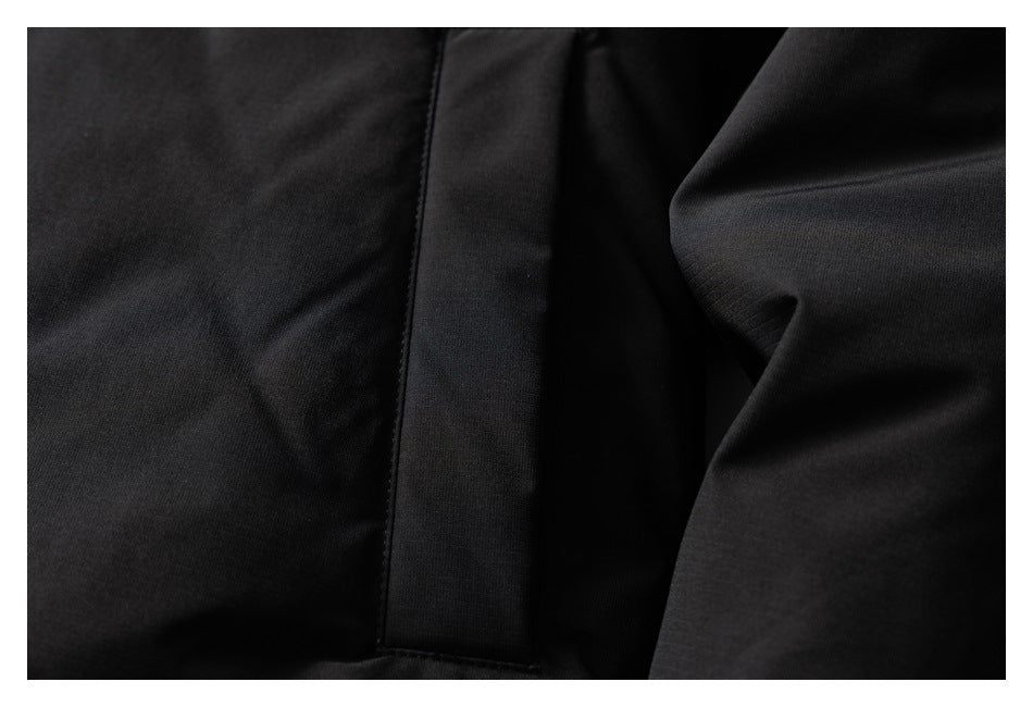 Close-up of black garment fabric with a vertical stitched panel and folded sleeve or fabric at the side.