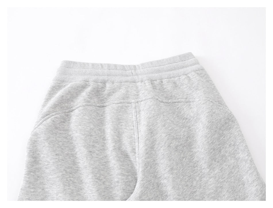 Close-up of the ribbed waistband and upper section of light gray sweatpants laid flat.