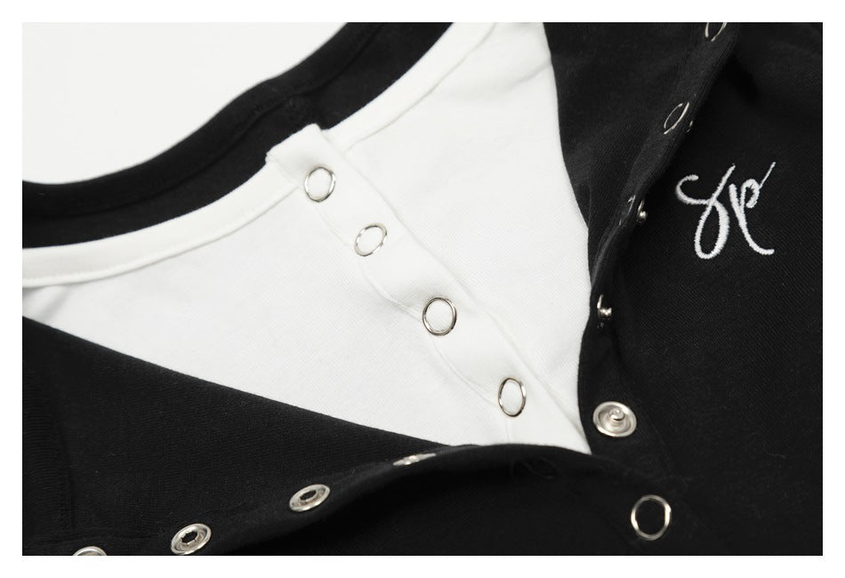 Close-up of a black-and-white garment with silver snap fasteners and small white script embroidery.