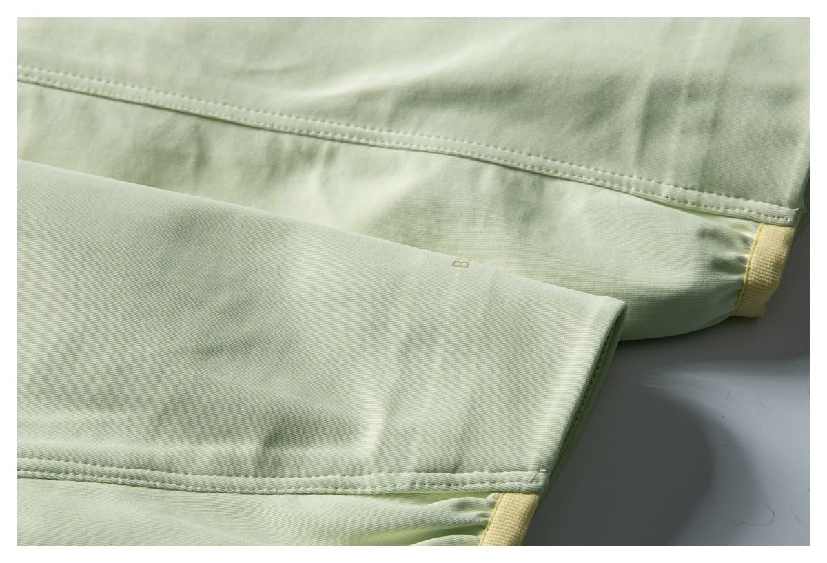 Close-up of pale green garment seams and a folded hem with yellow trim.
