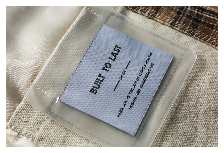 Close-up of a garment label reading “BUILT TO LAST” on beige fabric with plaid trim.