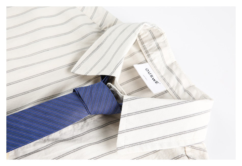 Close-up of the beige striped shirt collar, attached white brand label, and a blue striped tie.