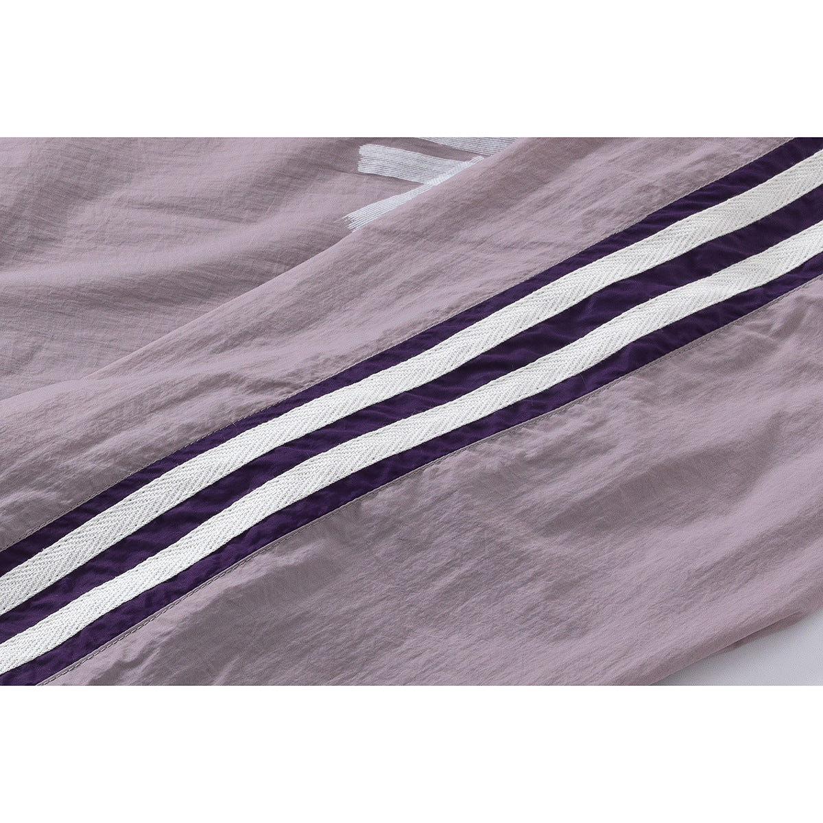Close-up of mauve jacket fabric with diagonal dark purple and white stripe panels.
