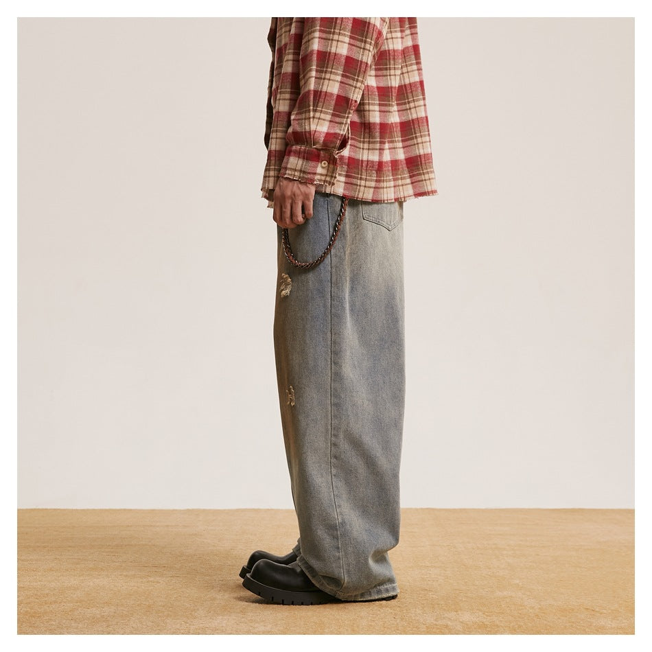 Side view of a model wearing loose gray washed jeans with distressed patches.