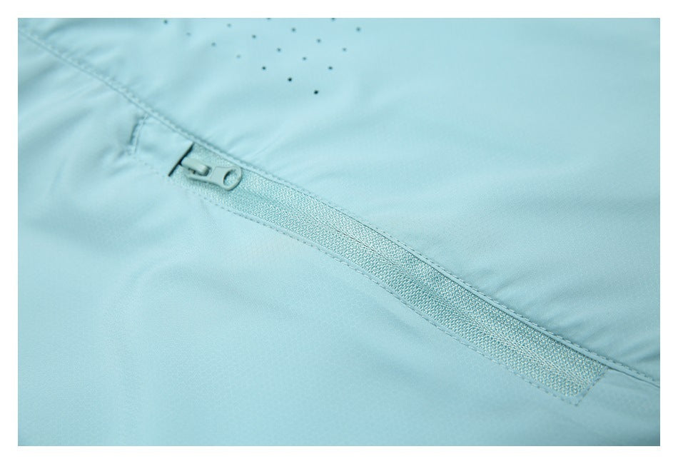 Close-up of a light aqua jacket's zip pocket and nearby perforated ventilation holes.