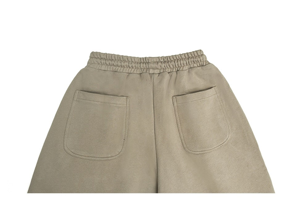 Cropped back view of taupe trousers with an elastic waist and two patch pockets.