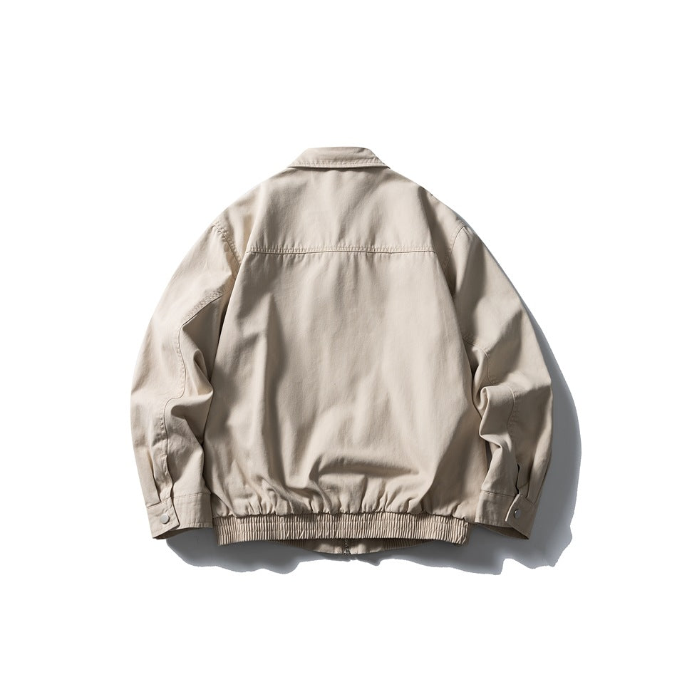 Back view of a light beige jacket with a pointed collar, shoulder seam and gathered elastic hem.
