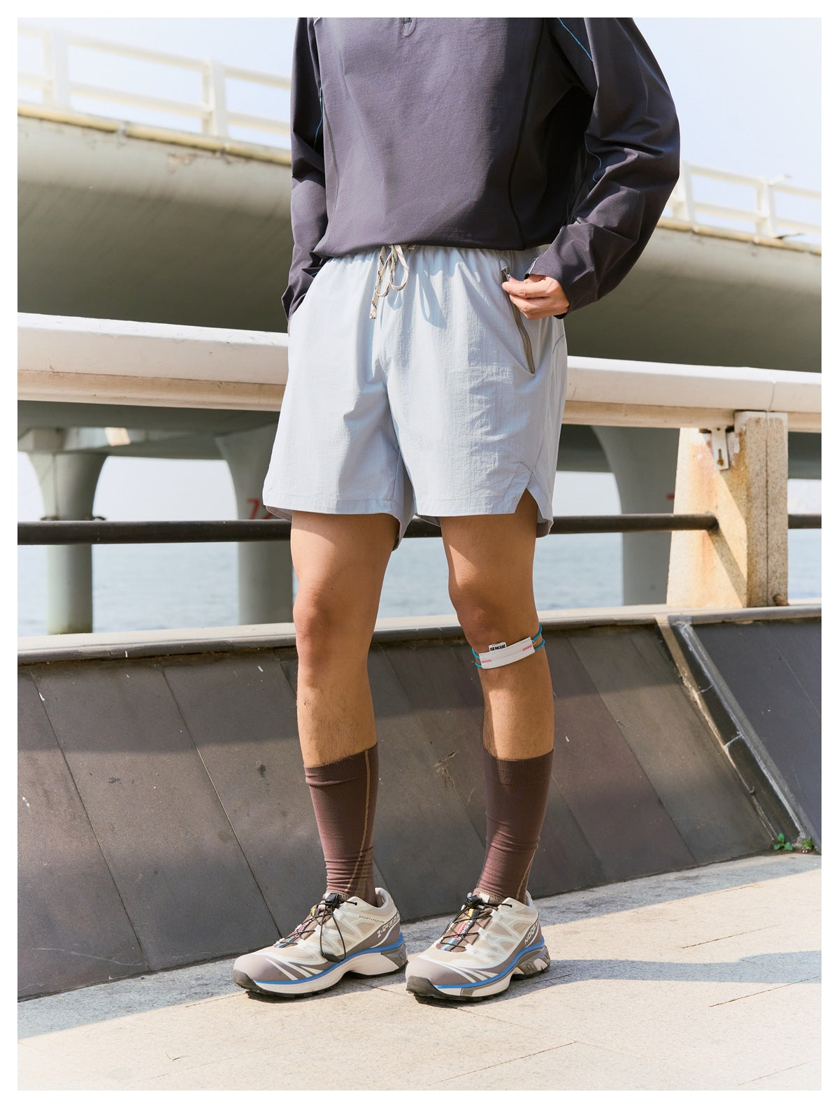 Front view of a model wearing pale gray drawstring running shorts with zippered pockets and side slits.