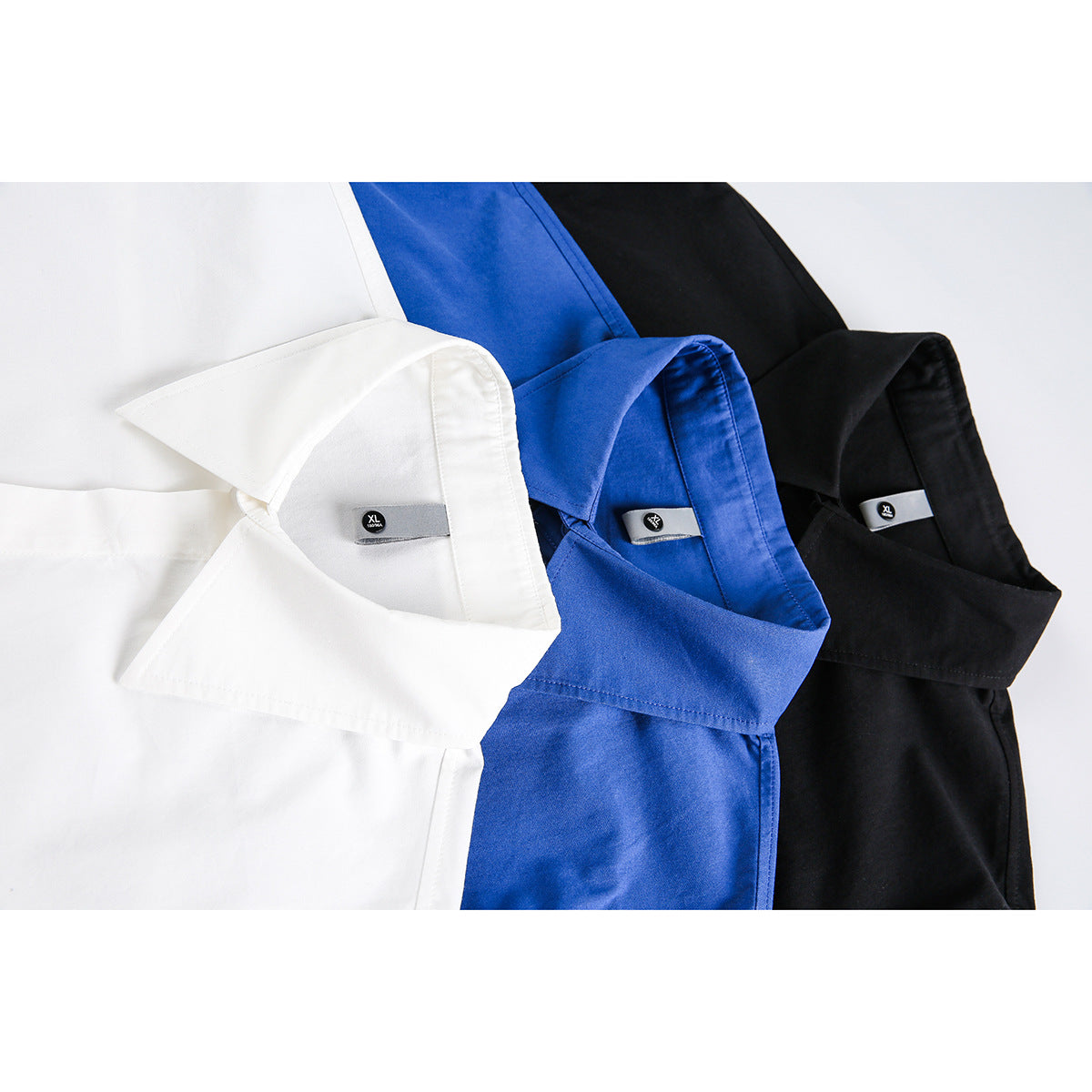 Close-up of white, royal blue, and black collared shirts, showing the collars and size tags.