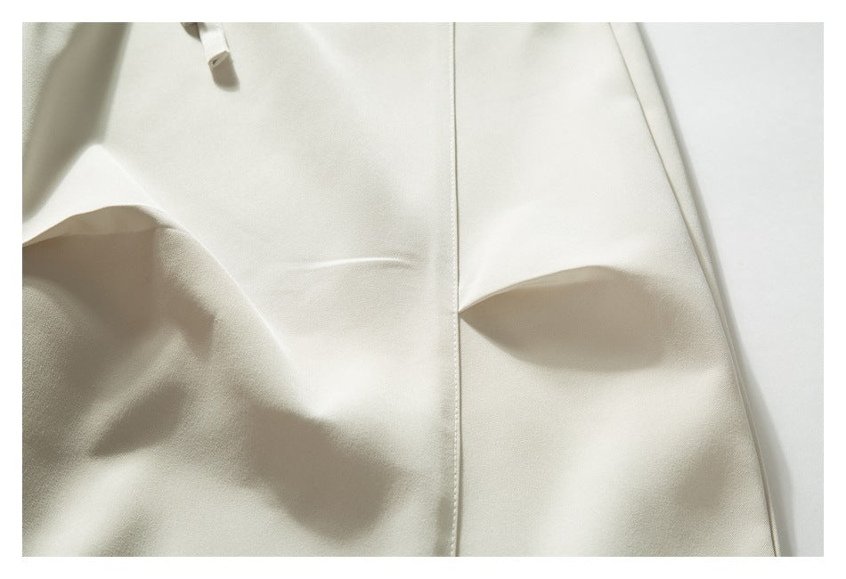 Close-up of ivory pants showing a vertical seam and a small drawstring end.
