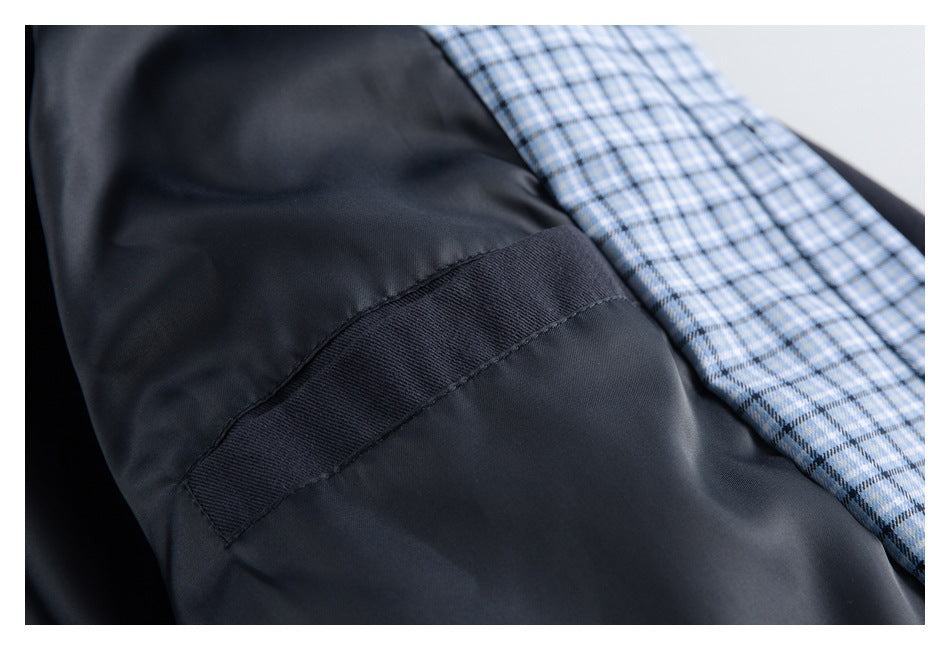 Close-up of the dark jacket's smooth inner panel and stitched seam beside light blue plaid lining.