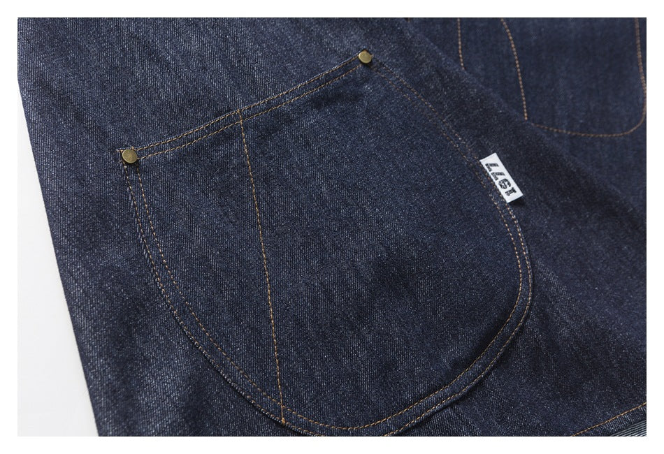 Close-up of a large rounded denim pocket with contrast stitching, metal rivets and a small sewn label.