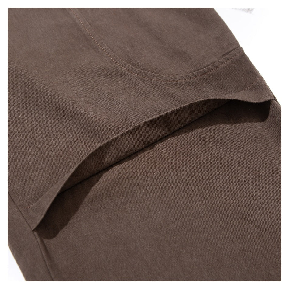 Close-up of a curved stitched seam and overlapping panel on brown pants.