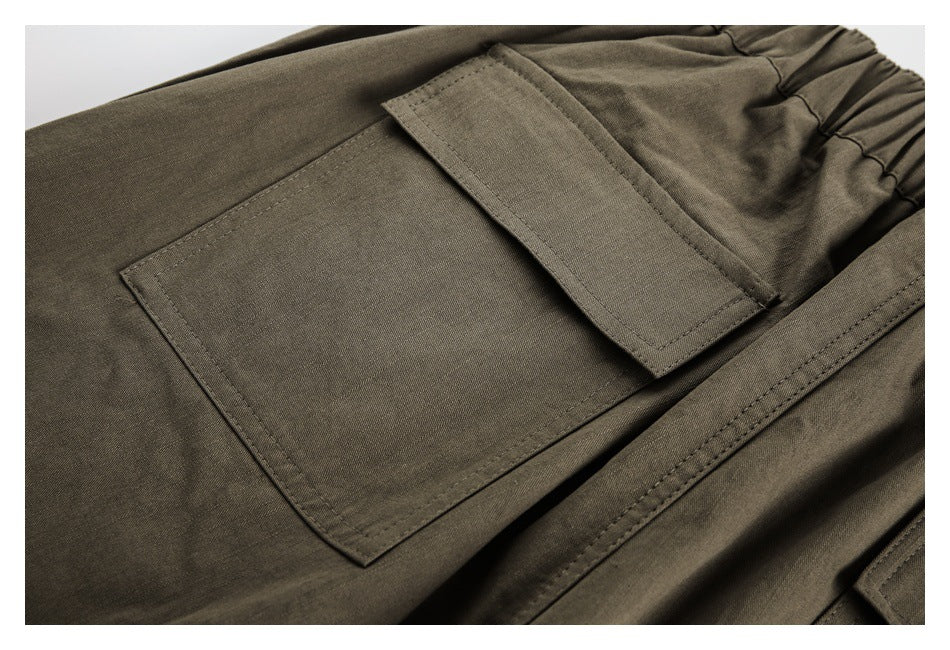 Close-up of an olive-brown trouser flap pocket beside the gathered waistband.