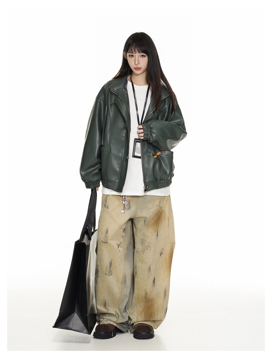 Model wearing a dark green faux-leather jacket over a white tee with wide-leg pants, holding a black tote bag