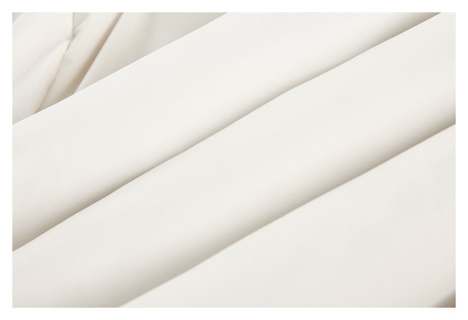 Close-up of smooth off-white garment fabric arranged in soft diagonal folds.