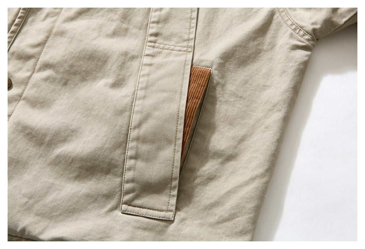Close-up of a long front pocket on the beige jacket, with a brown corduroy panel visible behind it.