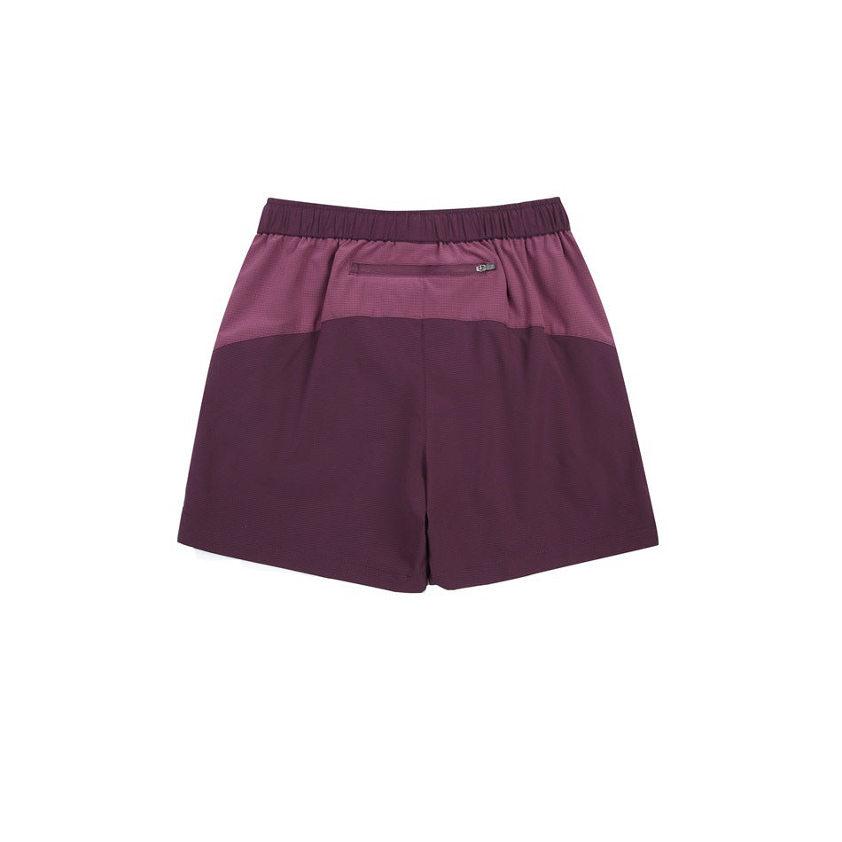 Back view of two-tone plum athletic shorts with an elastic waistband and a small zip pocket.
