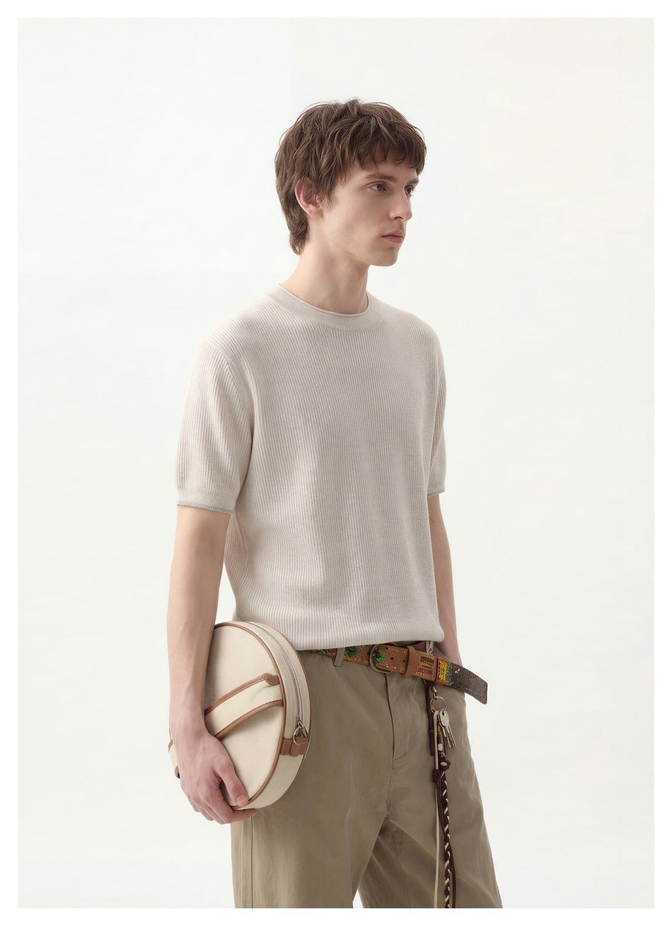Three-quarter view of a model wearing an ivory short-sleeve knit crewneck and taupe trousers.