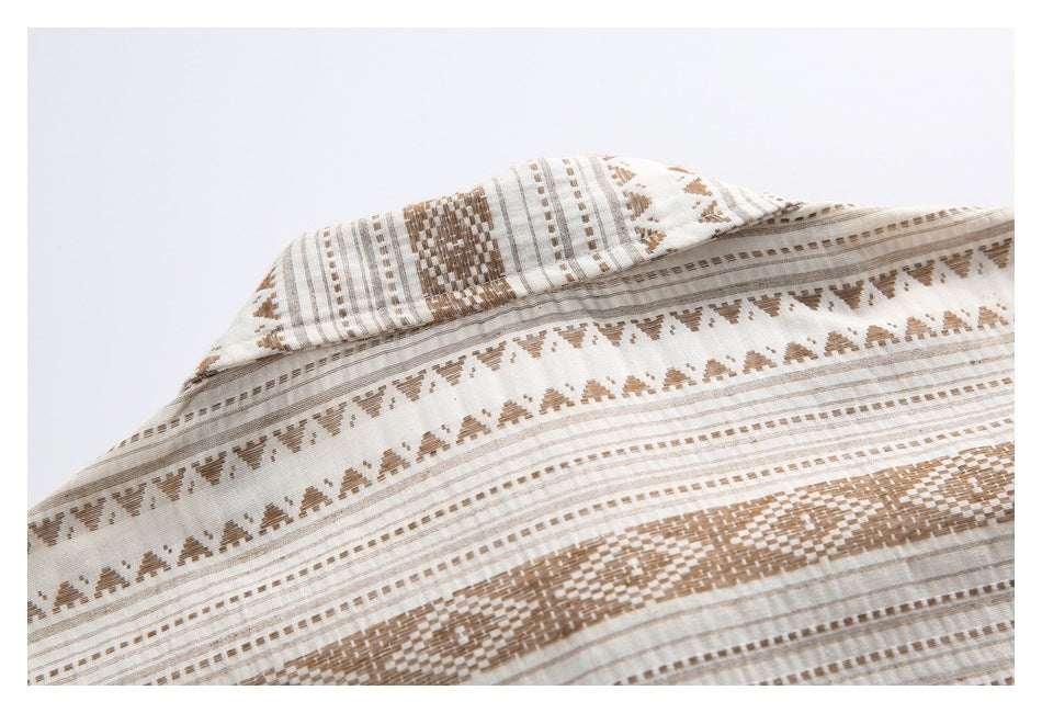 Close-up of the folded collar and patterned fabric, with brown geometric bands on a cream background.