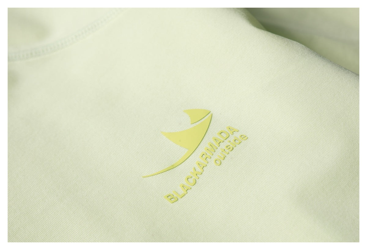 Close-up of a pale yellow-green garment showing a yellow BLACKARMADA Outside logo print.