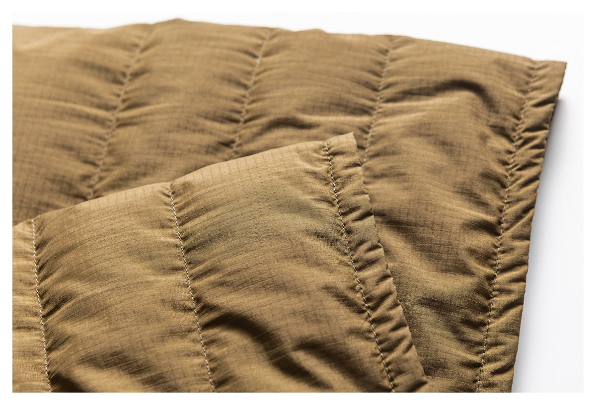 Close-up of brown quilted jacket fabric, showing parallel stitched channels and a folded edge.