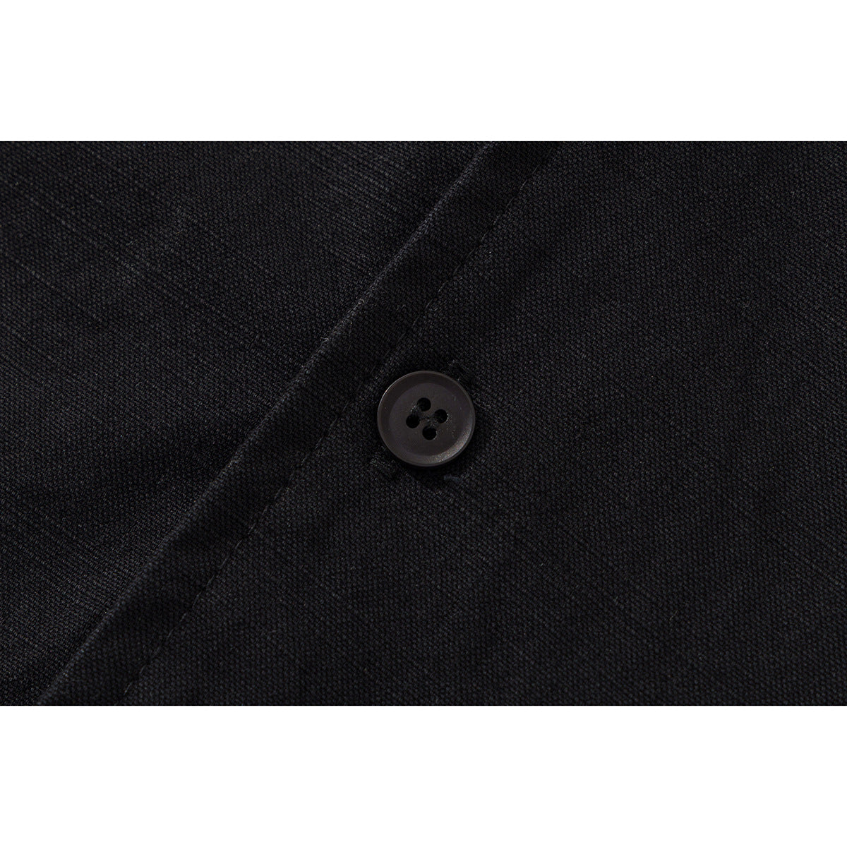 Close-up of a dark four-hole button on black shirt fabric.