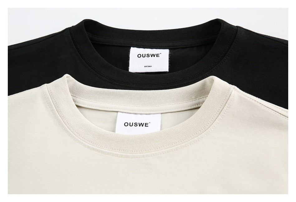 Close-up of cream and black T-shirt collars with OUSWE labels.