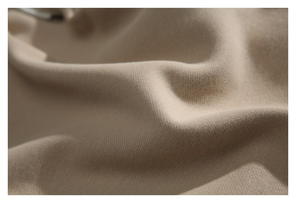 Extreme close-up showing the fine knit texture and folds of beige garment fabric.