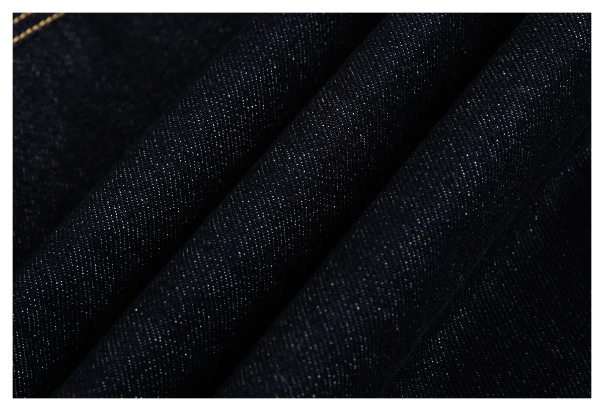 Close-up of dark indigo denim fabric arranged in soft folds, showing its woven texture.