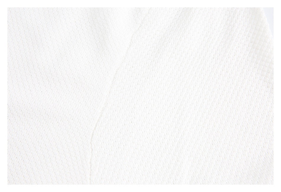 Close-up of white textured knit fabric with a subtle seam.