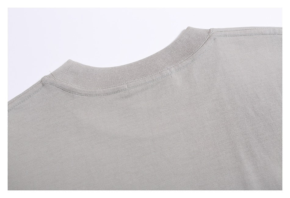 Close-up of a light gray garment’s ribbed crew neckline and shoulder seams against a white background.