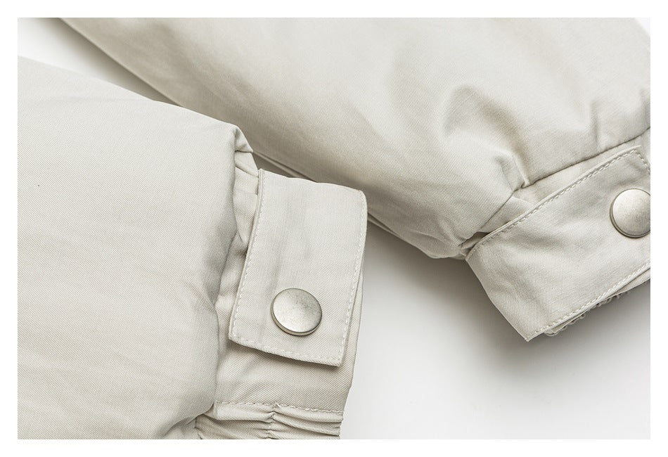 Close-up of a light beige jacket cuff with adjustable snap-button tabs.