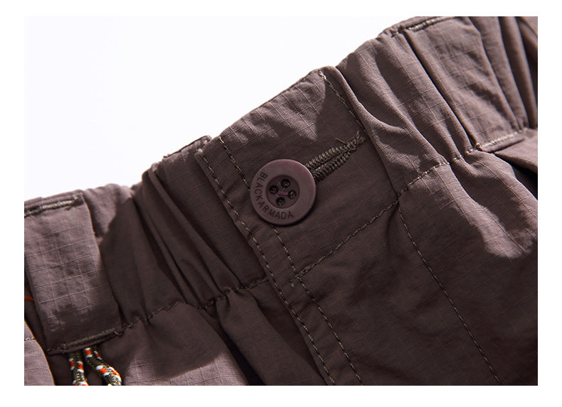Close-up of the mauve pants' waistband button, gathered elastic, and stitched front closure.
