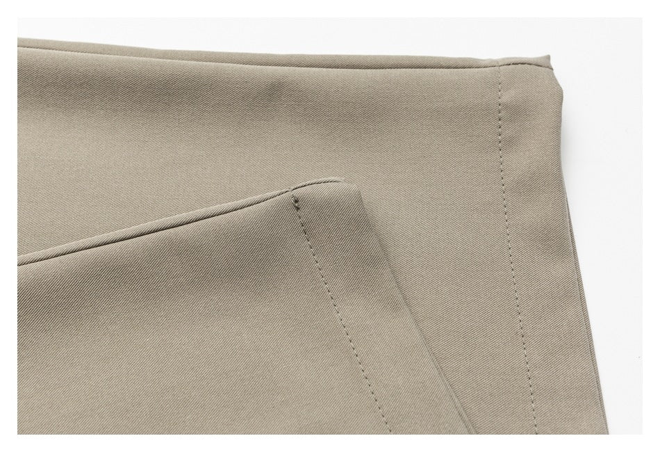 Close-up of taupe trouser fabric and a stitched seam near the edge.