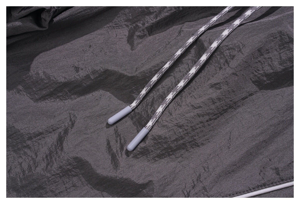 Close-up of two white-tipped drawcords against the crinkled charcoal gray pants.
